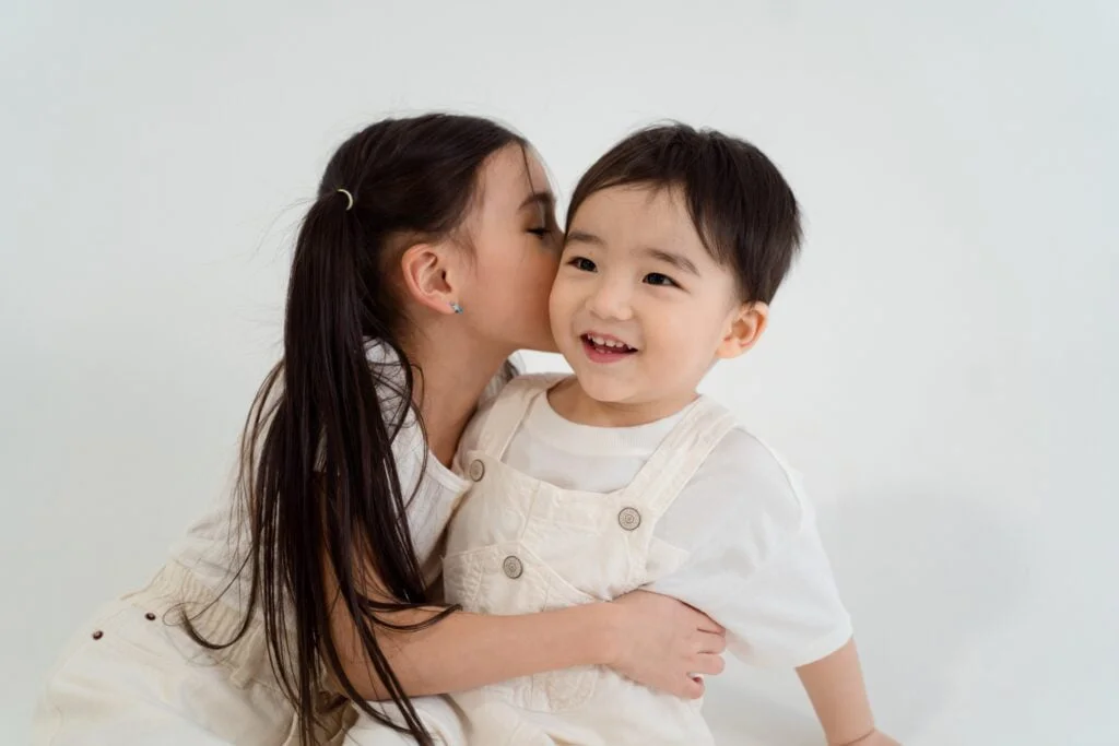 Big sister is kissing little brother