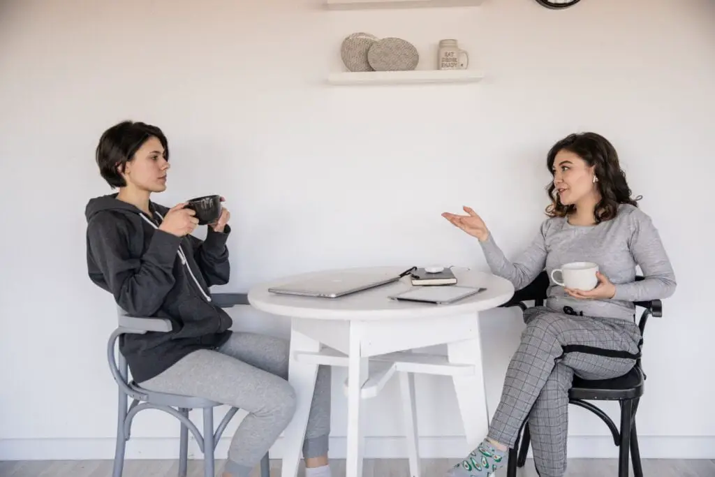 Two women are talking to each other drinking tea
